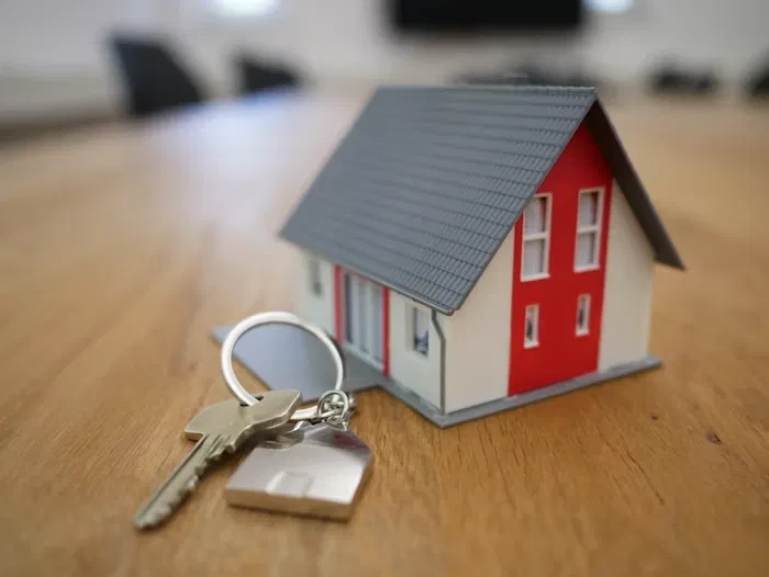 Maqueta de una vivienda con llaves sobre una mesa de madera