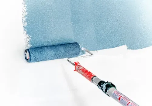Rodillo aplicando pintura azul sobre una pared